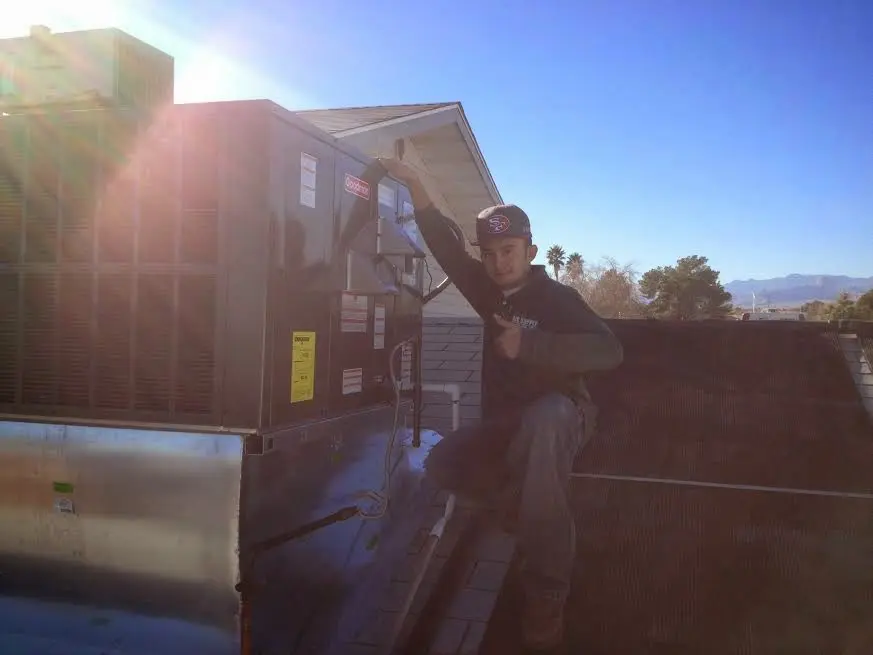 HVAC technician performing Air Duct Cleaning on a rooftop unit in Yucca Valley