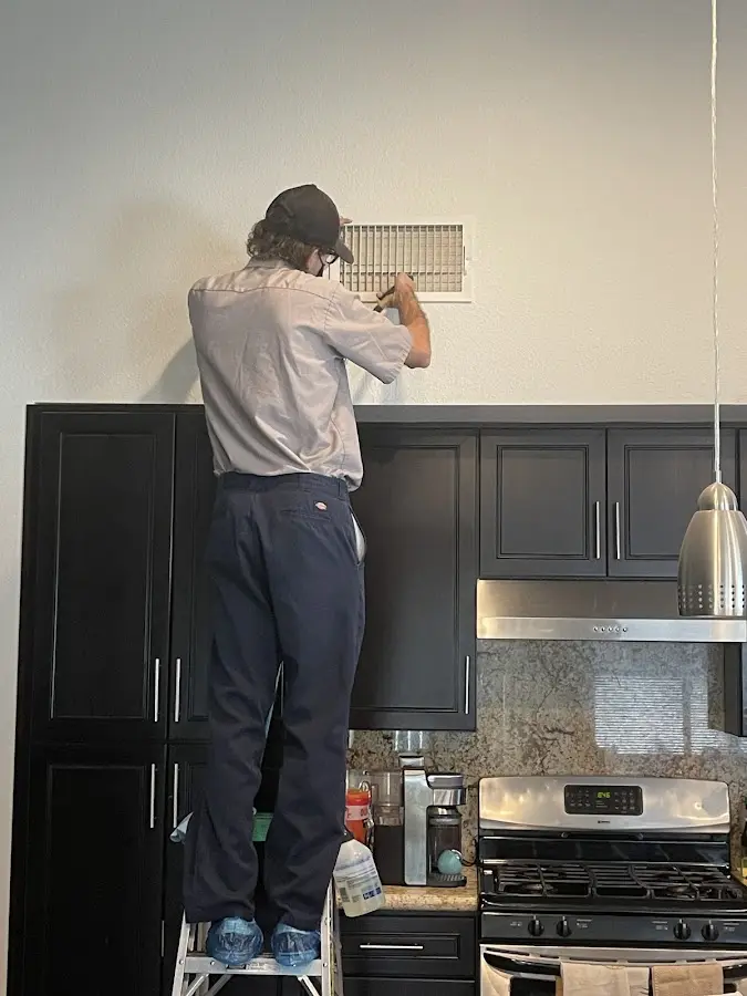 Technician inspecting an air vent during HVAC service in Yucca Valley